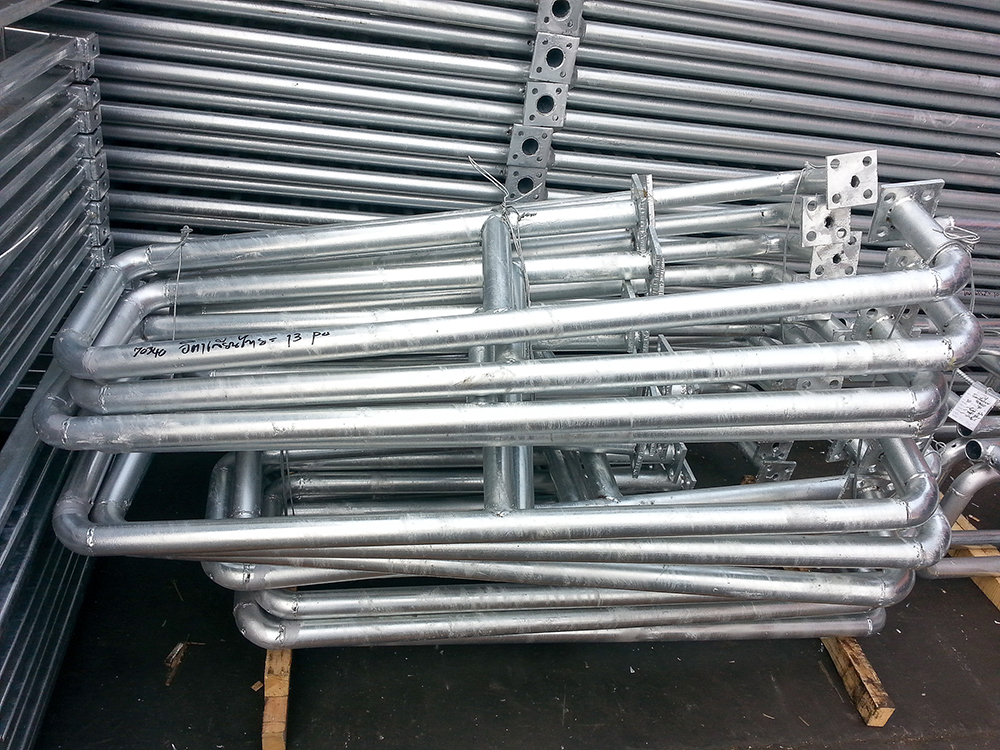 Stack of galvanized steel fabricated frames with welded joints and mounting brackets, stored on a pallet in a warehouse.