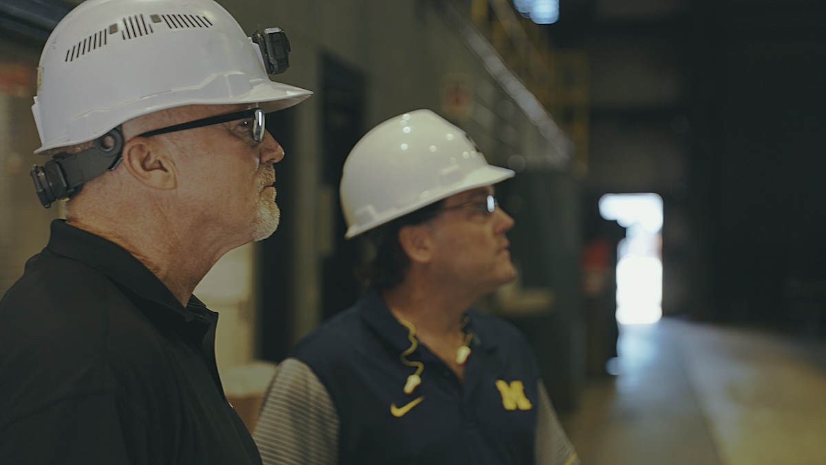 Two engineers wearing white safety helmets observing production processes inside Kenwal Steel facility during operational inspection.
