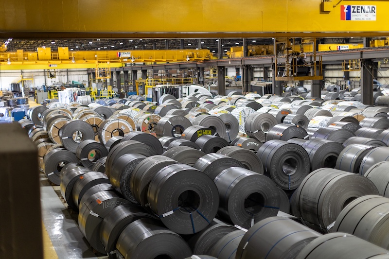 Wide view of stacked steel coils inside Kenwal Steel’s processing facility, showing extensive inventory of flat-rolled steel under large overhead cranes.