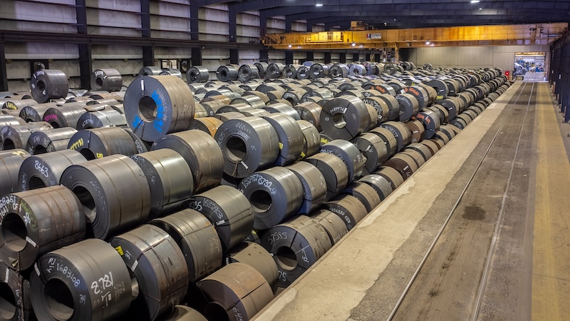 Steel Coil Inventory in Storage Warehouse | Kenwal Steel Distribution Rows of large flat-rolled steel coils stored in a warehouse at Kenwal Steel, showcasing organized inventory management and industrial distribution operations.